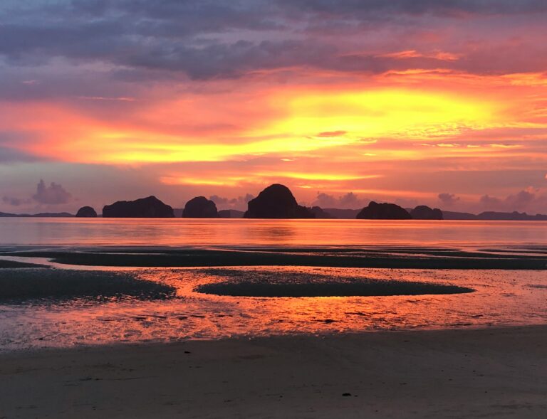 a vibrant orange and yellow sunset at the beach in Tubaek Krabi
