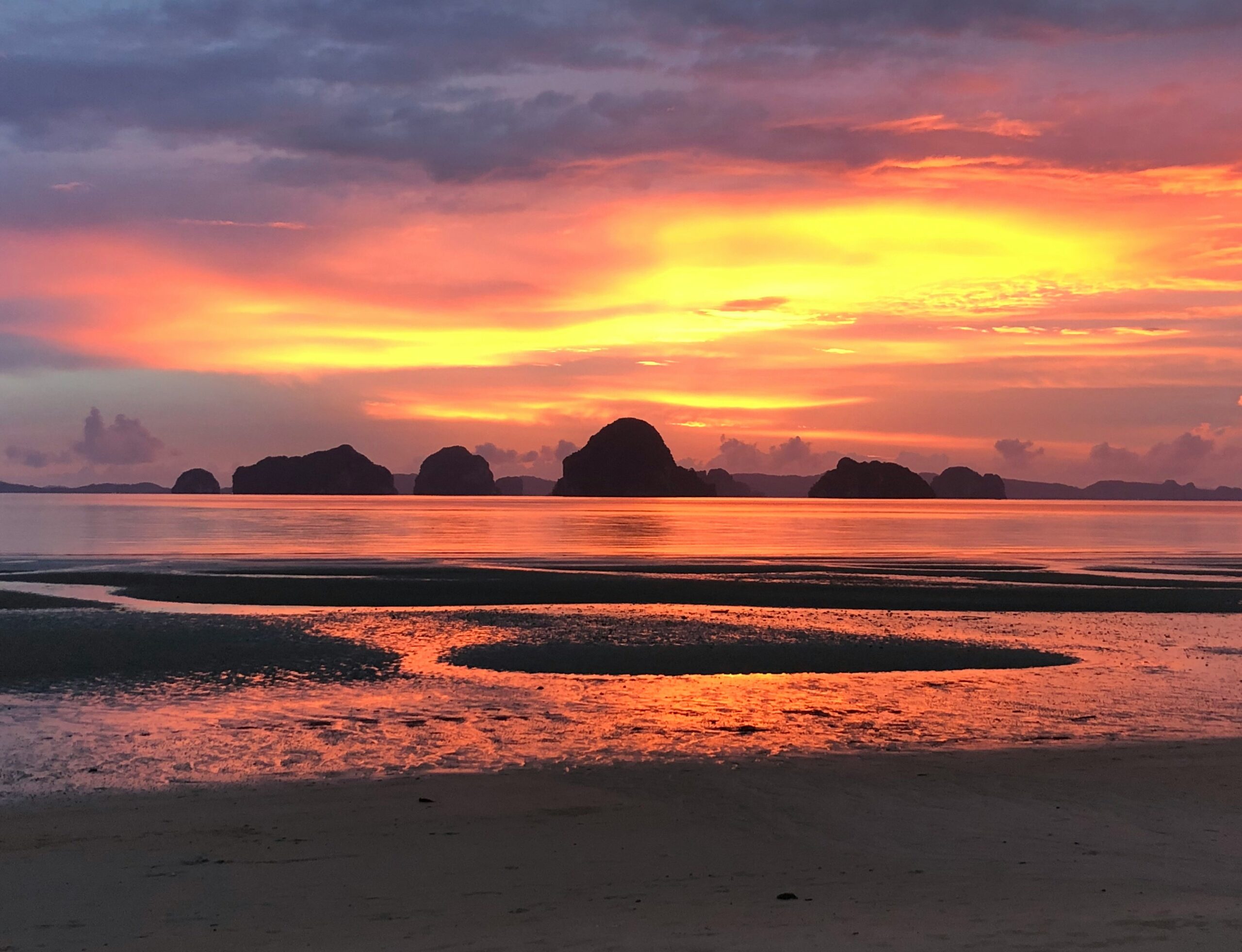 a vibrant orange and yellow sunset at the beach in Tubaek Krabi