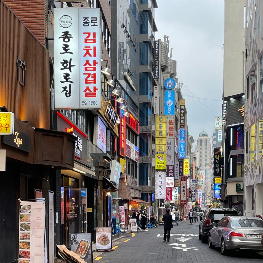 several signs for restaurants and bars on a notable street in Seoul, South Korea