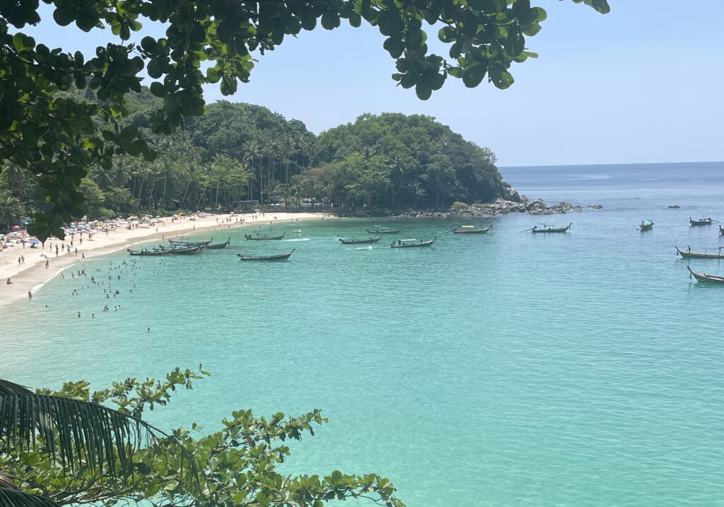 several tourist and Thai longtail boats on the shores of Freedom Beach in Phuket 
