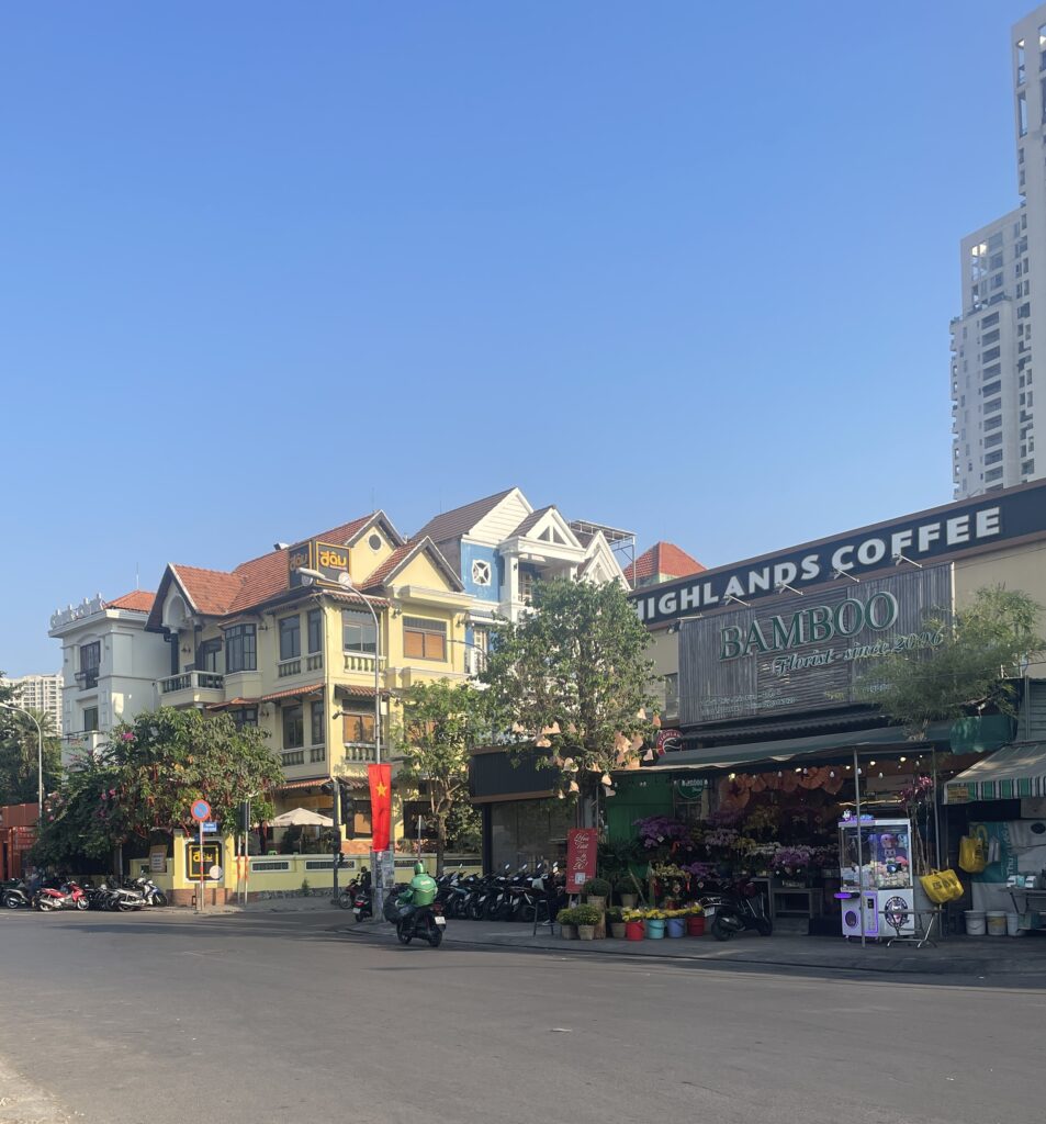 man driving by on a scooter in a empty road amongst many buildings on a beautiful clear day in Thao DIen area in Ho Chi Minh City