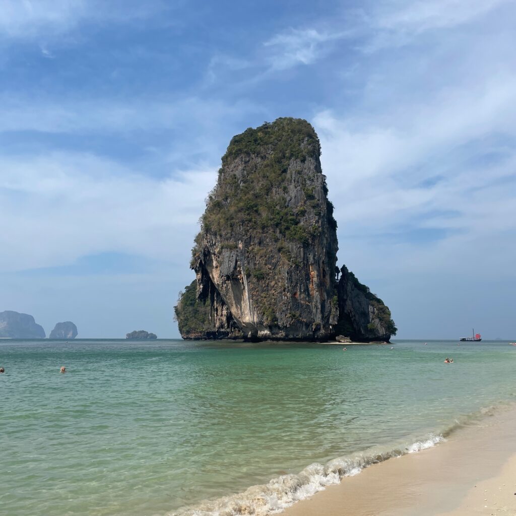a large limestone in the sea seen from the shores of Phra Nang Cave Beach in Railay, Krabi, Thailand