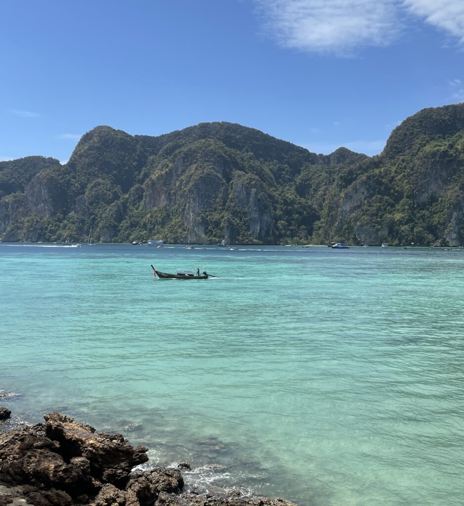 a Thai longtail boat sailing along the picture perfect turquoise waters in Koh Phi Phi