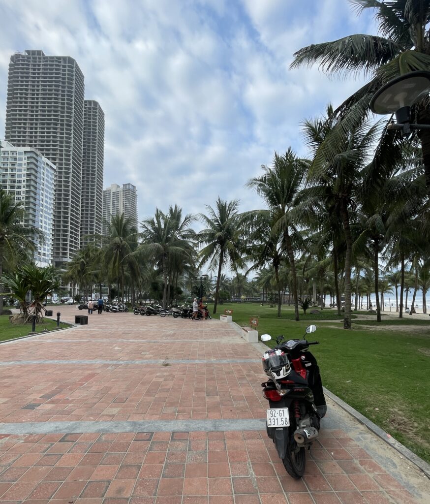 a beautiful paved boardwalk amongst My Khe Beach and several condo towers in the distance