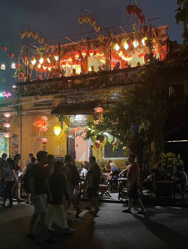 many tourists walking in the Hoi An Ancient Town with many lit lanterns in the background
