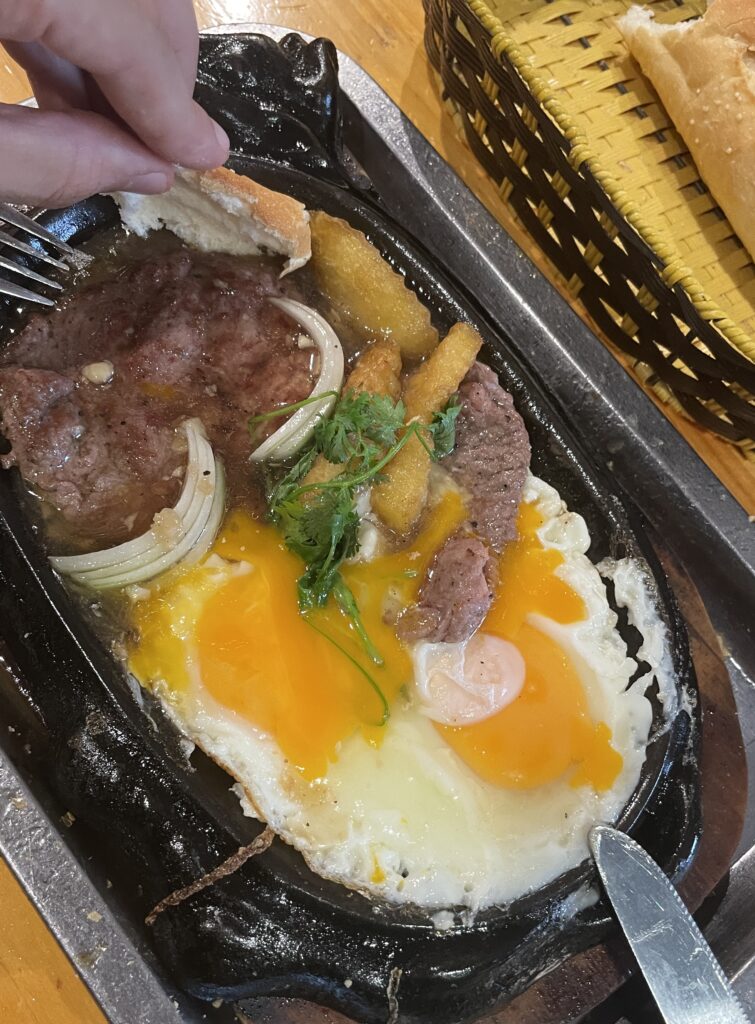 a sizziling plate of Bo Ne, a popular Vietnamese breakfast dish