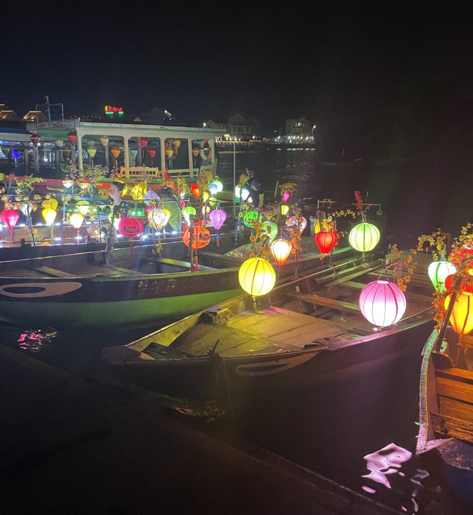 several lanterns hanging on boats on the river during the night time in Hoi An, Vietnam