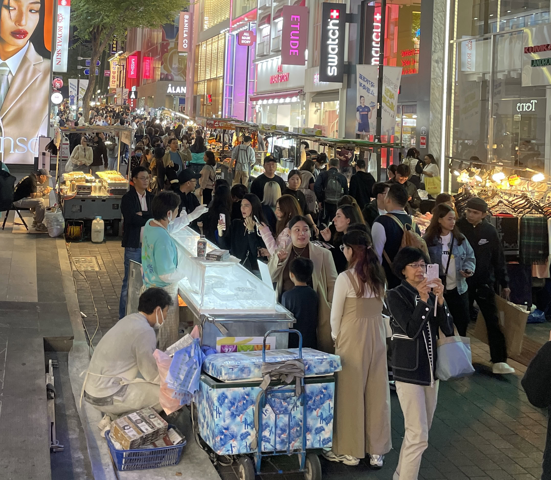 Several vendors selling various street foods at the Myeongdong night market as many tourists and locals explore