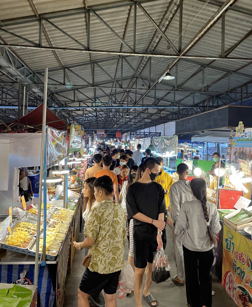 many locals walking and browsing street food at the Train Market in Bangkok