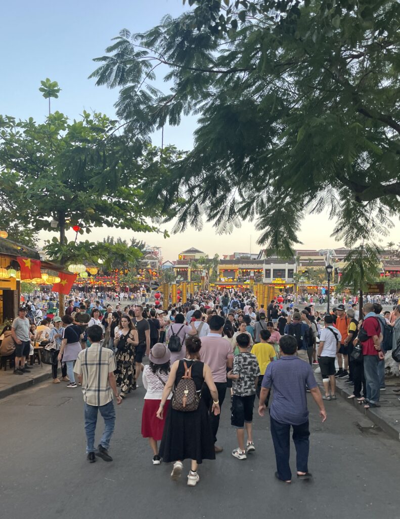 dense crowds of tourists heading towards the bridge in Hoi An, Vietnam