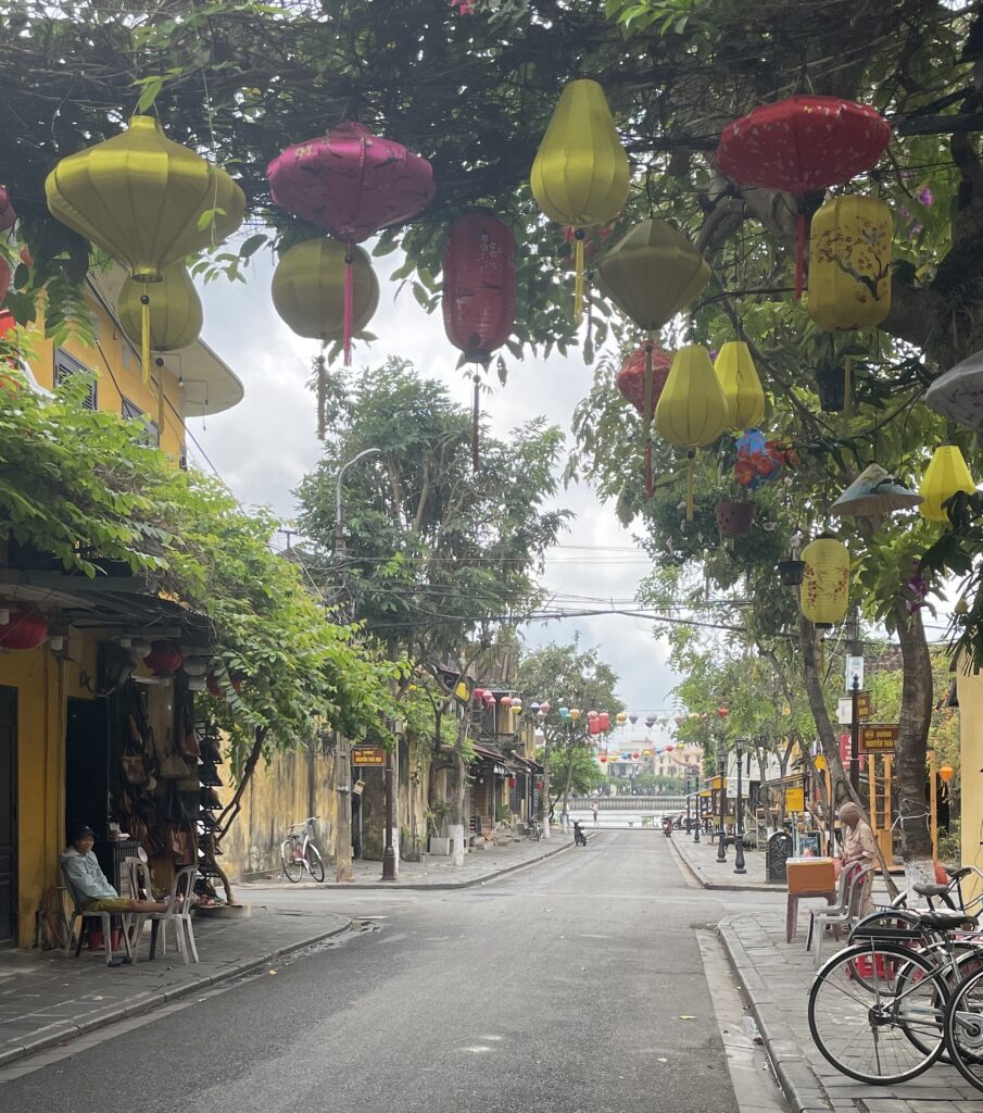 lanterns hung on trees with a river in the distance in the Old Town of Hoi An, Vietnam