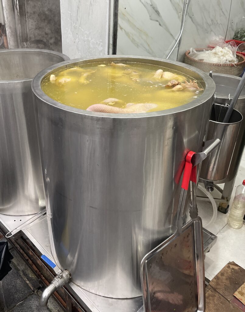 a large metal cipher full with chicken broth for Pho ga 