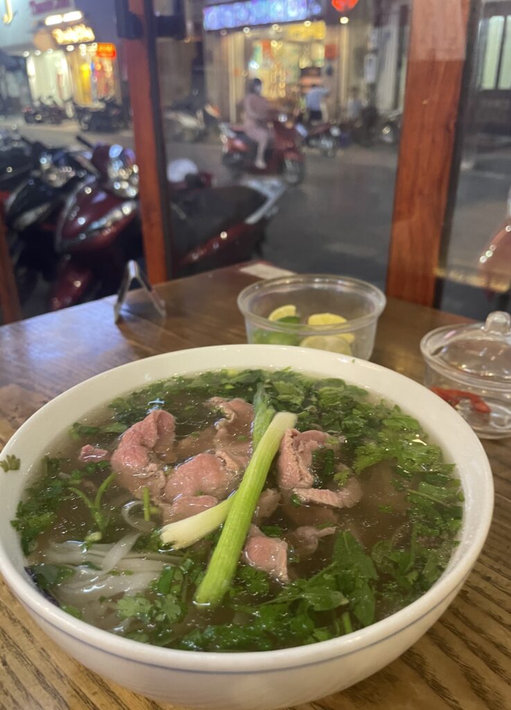 a steaming bowl of pho served by the window