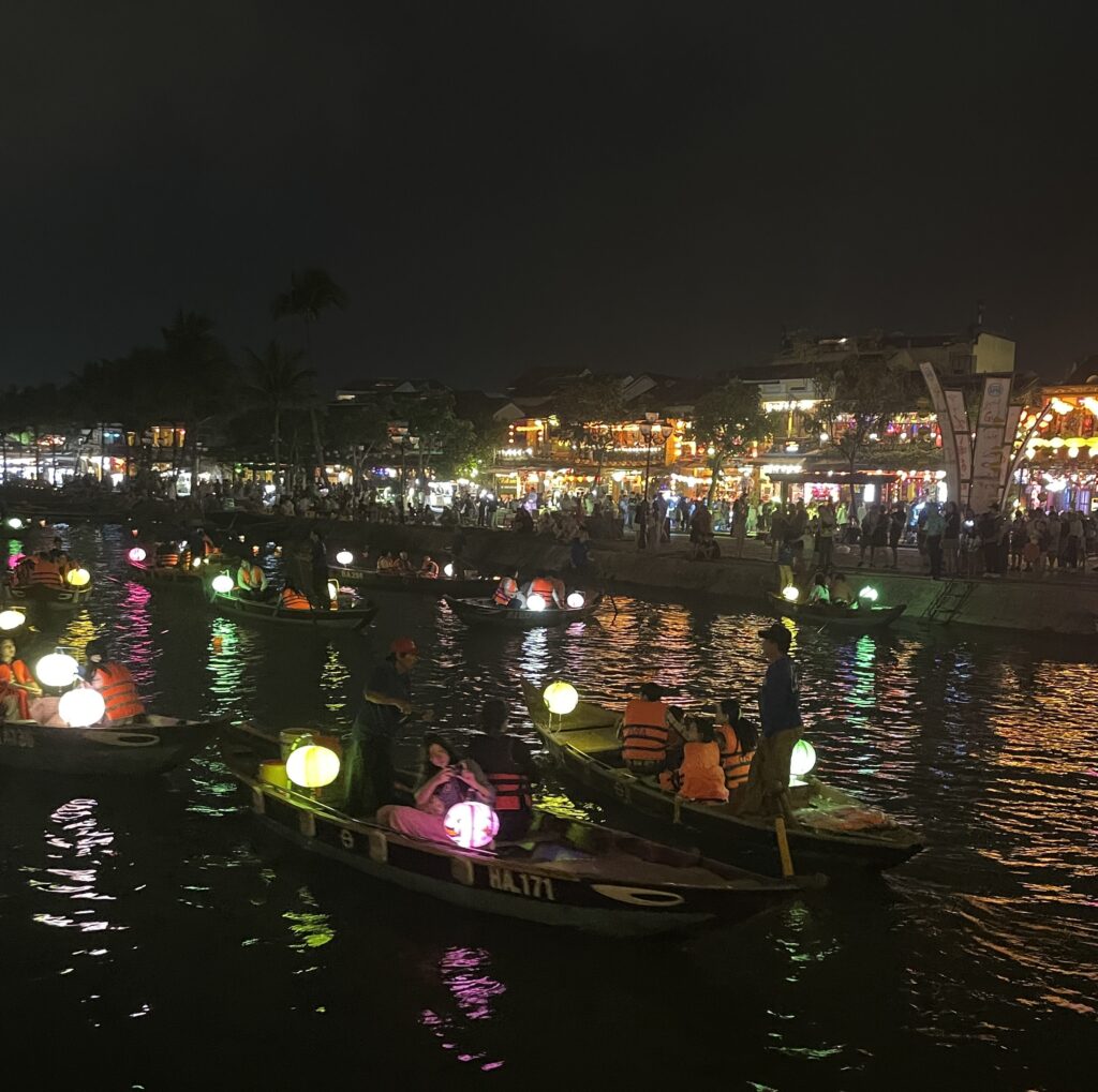 several tourists on boat rides in the evening among many lantern lights in Hoi An, Vietnam