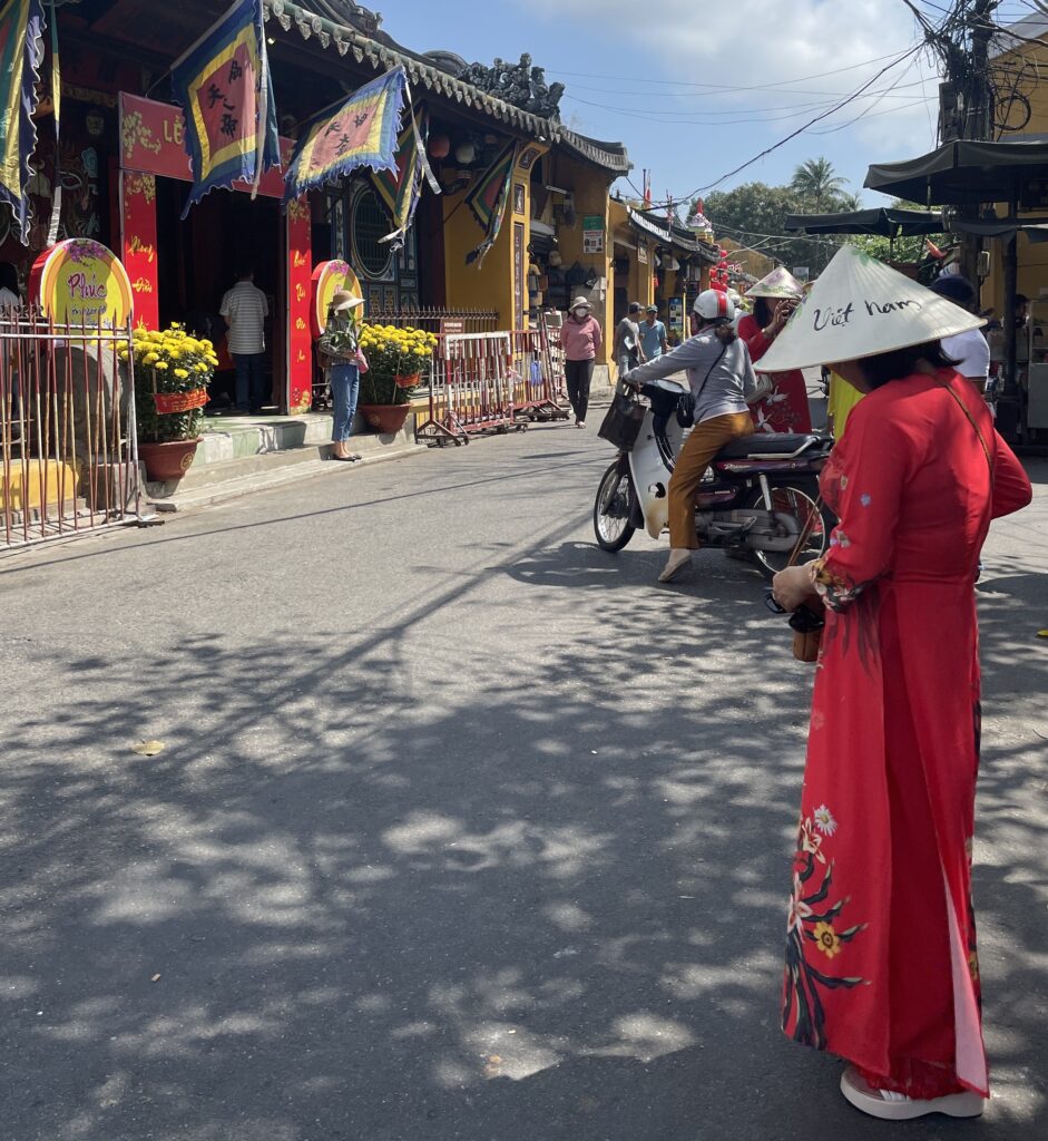 a woman in a red dress with a classic Vietnamese farmer hat in the Old Town of Hoi An
