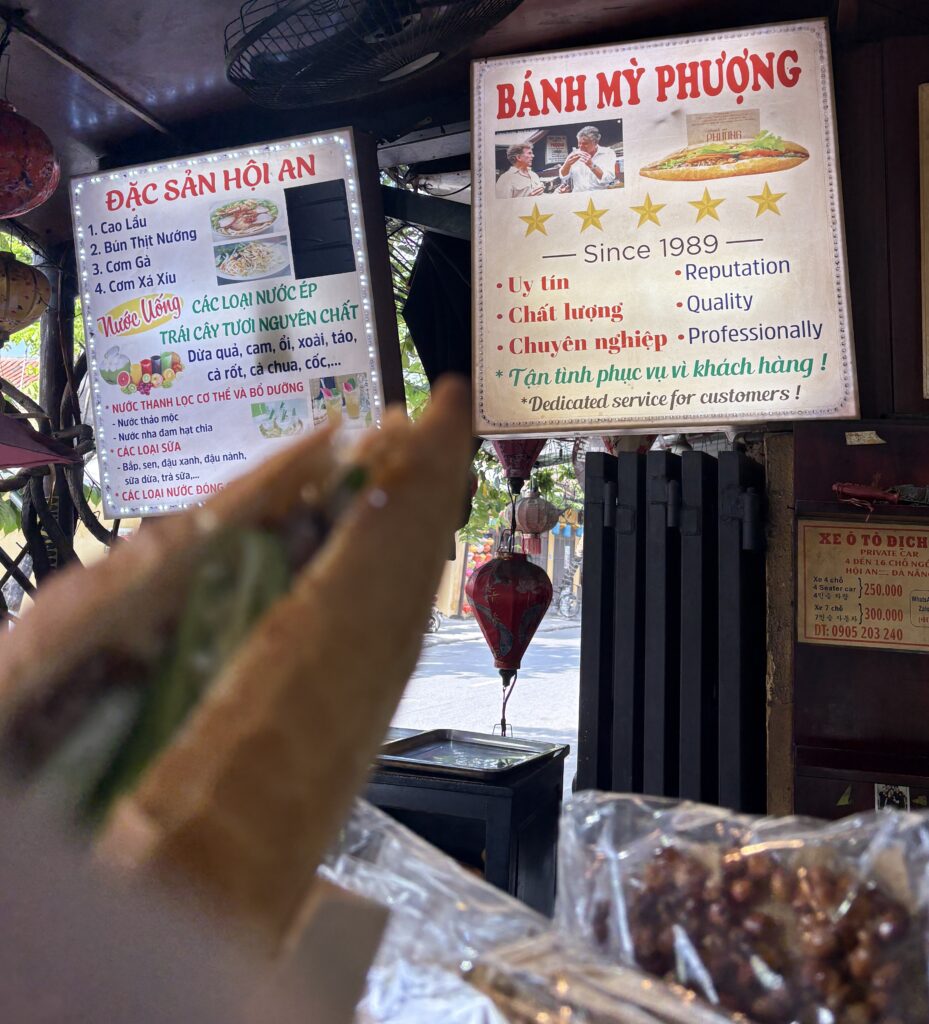 banh mi sandwich held up by the store sign in Hoi An 