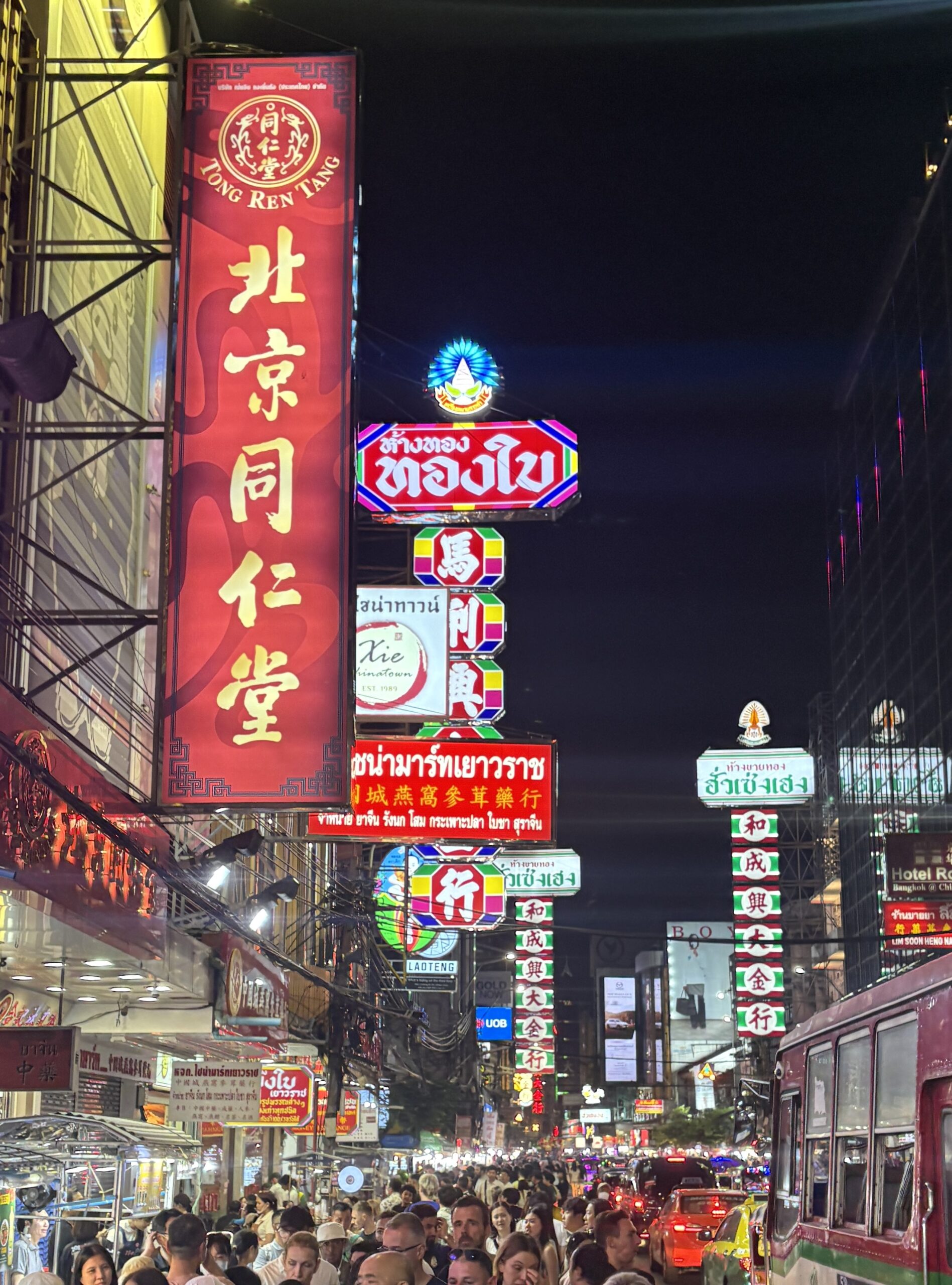 Bustling street scene in Bangkok’s Chinatown with neon signs and traffic