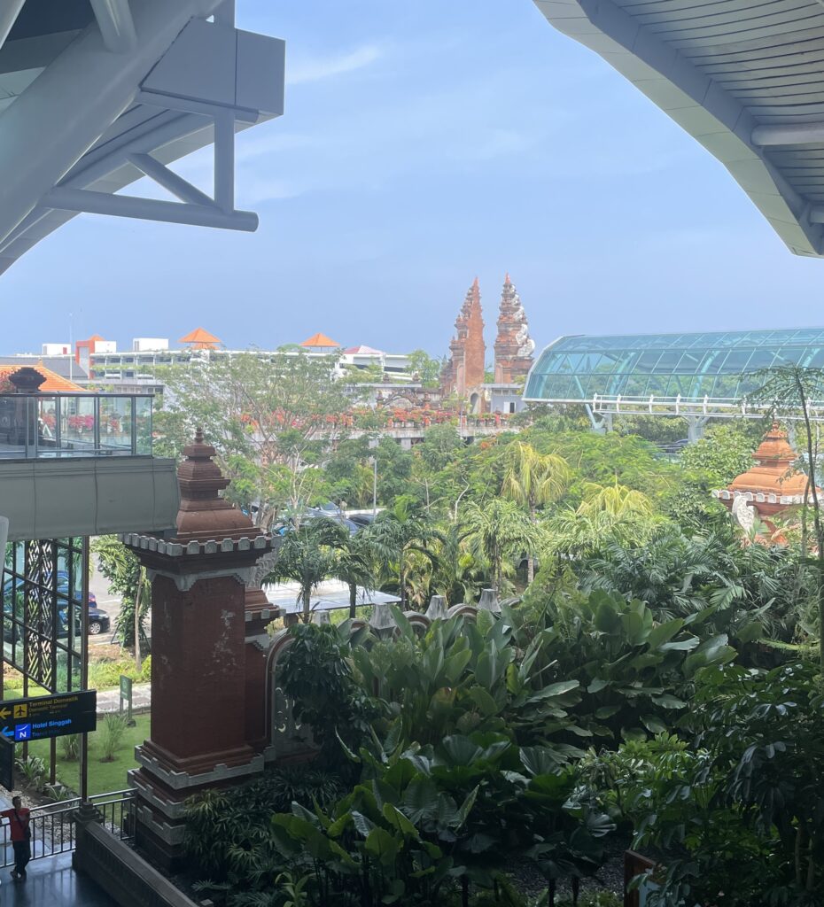 View of Bali Ngurah Rai Airport with palm trees and traditional Balinese-style buildings, showcasing the island’s cultural architecture upon arrival.