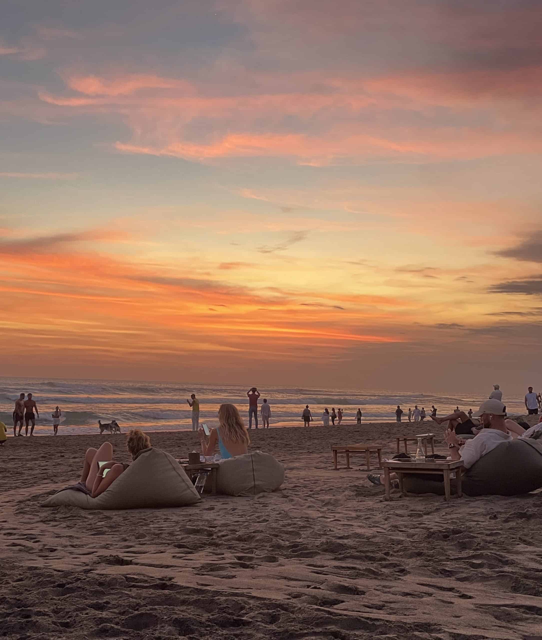 Golden sunset over Canggu Beach in Bali, with surfers in the distance and waves gently rolling onto the shore.