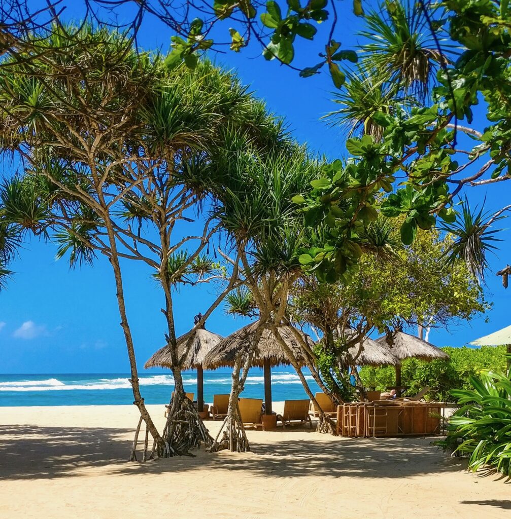 Scenic view of Nusa Dua Beach in Bali featuring golden sand, swaying palm trees, and perfect blue skies, an ideal spot for a peaceful beach day.