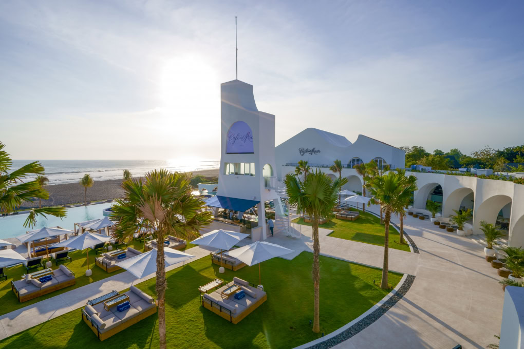 Elegant oceanfront view of Café Del Mar Bali with white sunbeds and infinity pool facing the sea