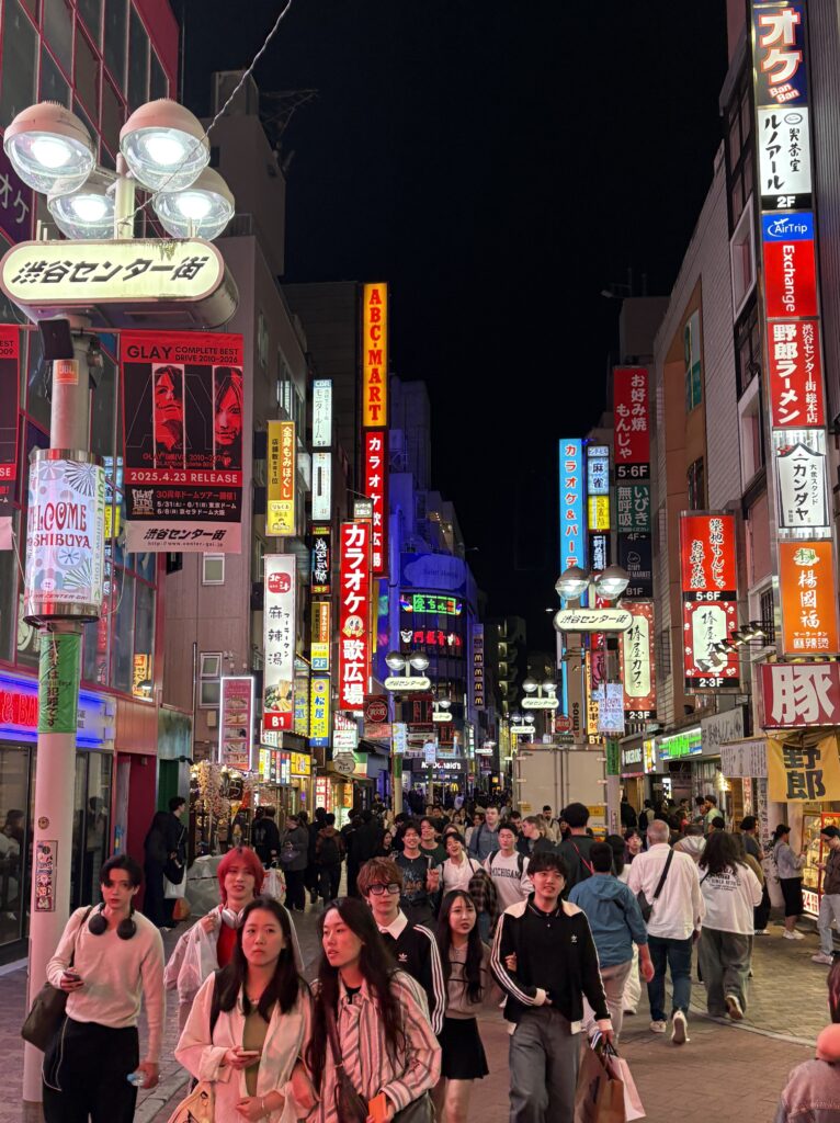 Crowds walking through Shibuya street with bright lit signs in the background