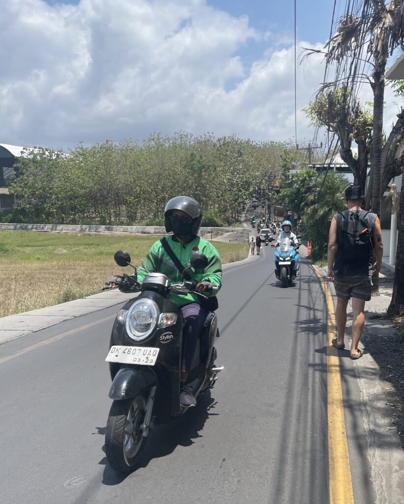 Grab motorbike driver navigating traffic on a scooter in Bali