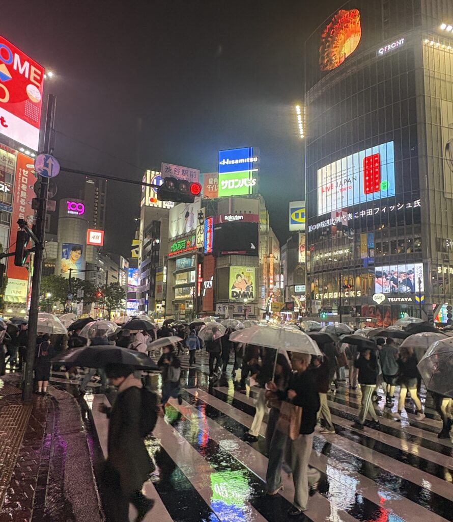 Shibuya Crossing in Tokyo on a rainy day with crowds holding colorful umbrellas