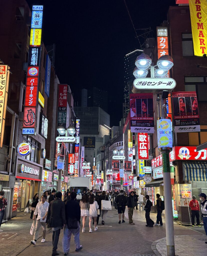 Crowds walking along a brightly lit street in Shibuya, one of the best areas to stay in Tokyo for nightlife and energy