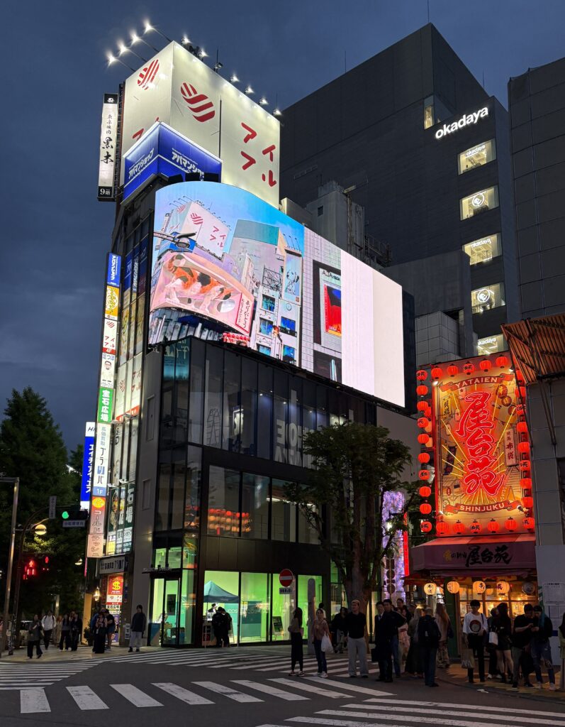 Shinjuku crosswalk at night with bright lights and illuminated signs