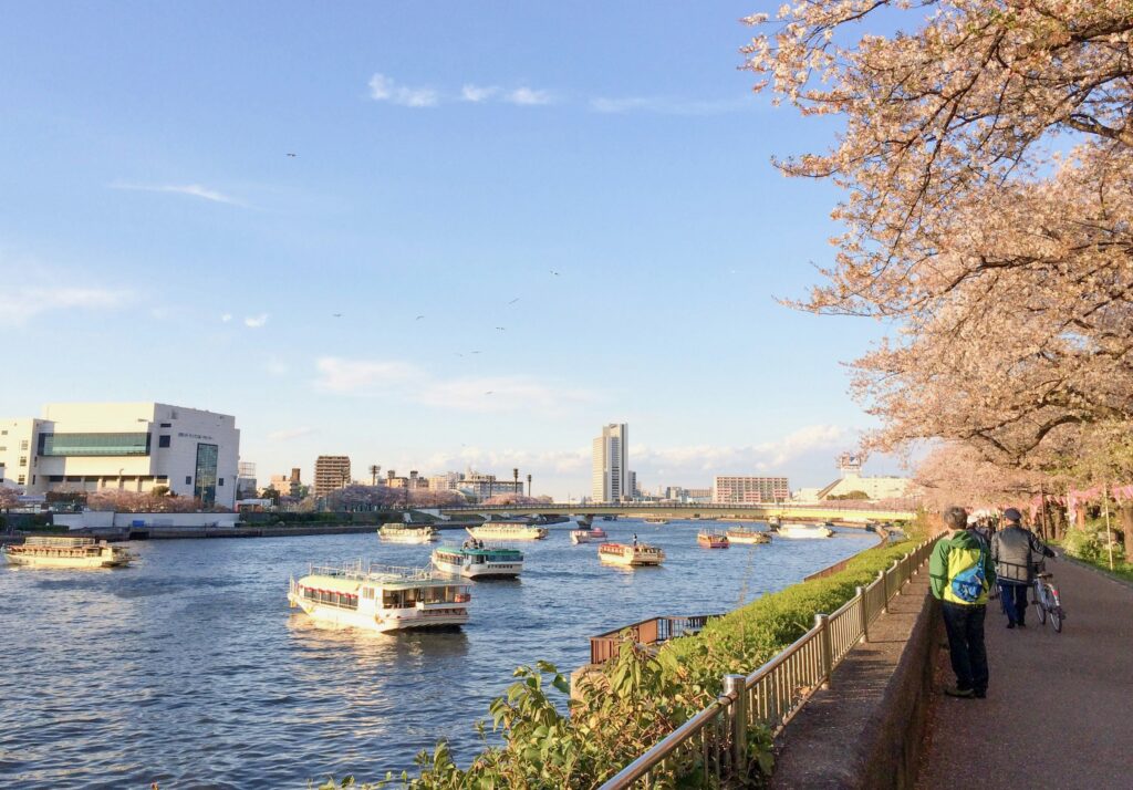 View of the Sumida River in Tokyo with boats cruising and city skyline in the background