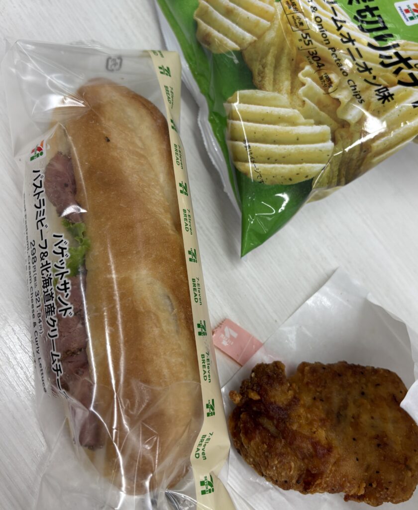 Beef pastrami sandwich from 7-Eleven Japan served with potato chips and a hot coffee on a convenience store table