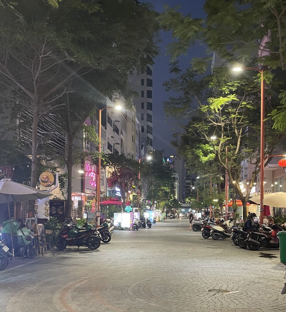 Cobblestone street lined with restaurants, massage shops, and local businesses in Da Nang’s An Thuong area, a popular digital nomad hub
