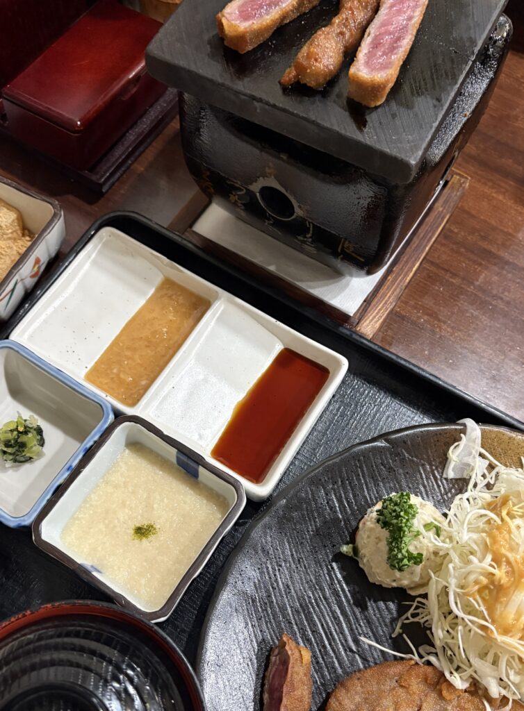 Beef katsu being grilled in Osaka, served with shredded cabbage salad and assorted side dishes