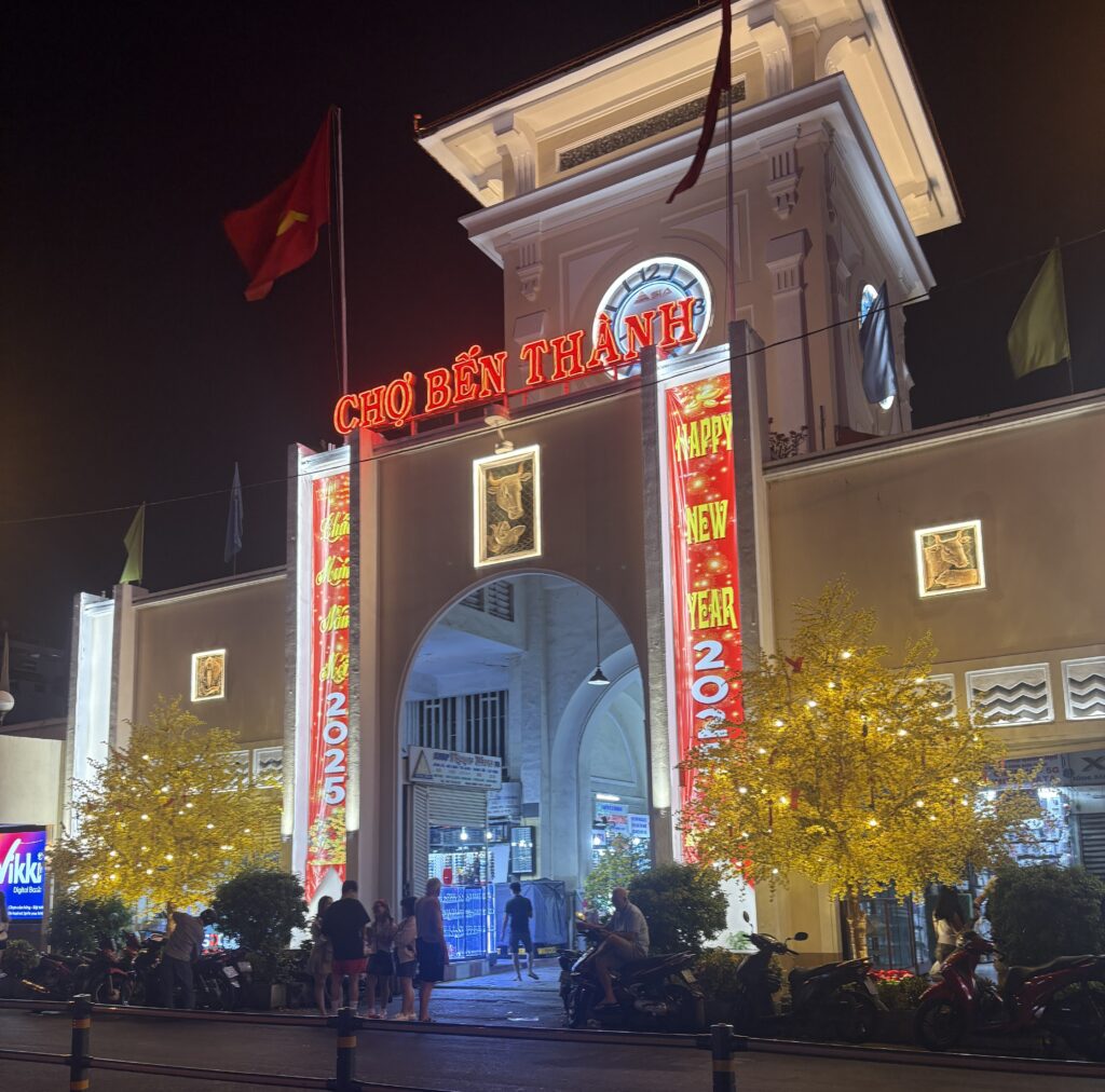 Front view of the illuminated Ben Thanh Market at night with bright signage in the Ben Thanh Market area