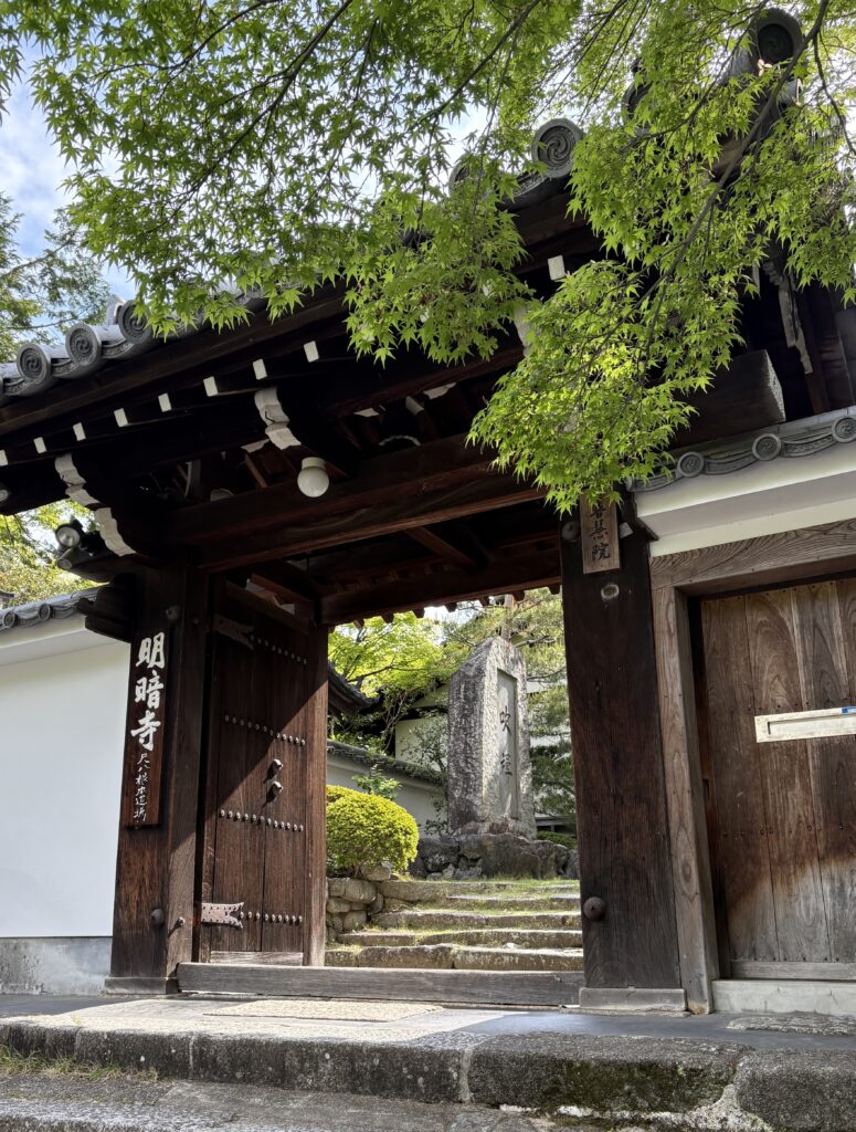 Traditional brown Japanese temple with a curved roof, surrounded by lush green nature in Kyoto.