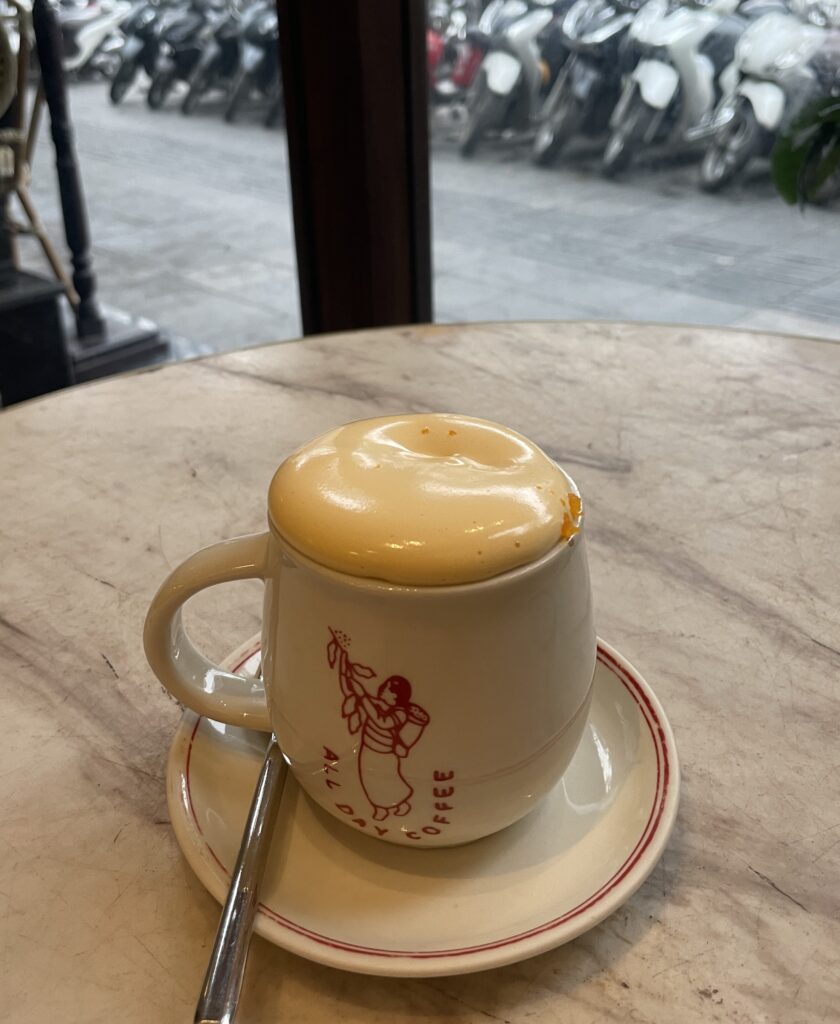 A perfectly foamy egg coffee served at a Hanoi café with a view of the bustling street outside.