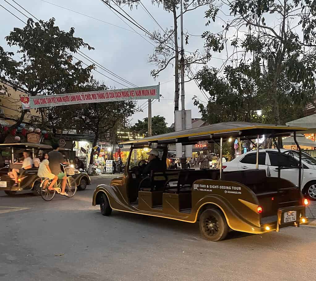 Electric shuttle vehicle driving through the lantern-lit streets of Hoi An Old Town.