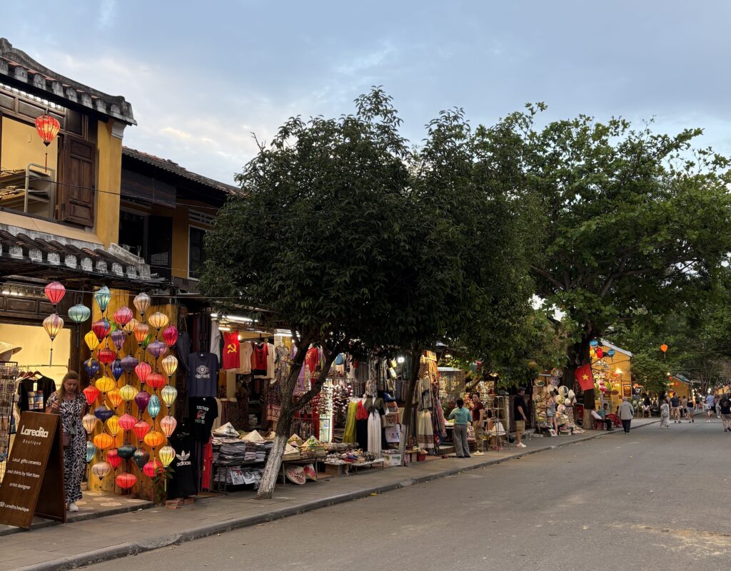 Empty street in Hoi An with shops on the left side during golden hour sunlight