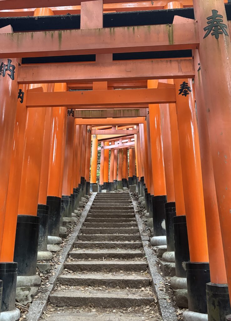 The famous uphill pathway at Fushimi Inari Shrine in Kyoto, lined with vibrant red torii gates and lush greenery.