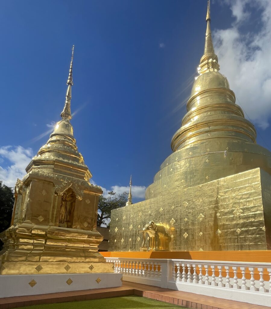 Two bright golden temples side by side under a clear blue sky in Chiang Mai’s Old City.
