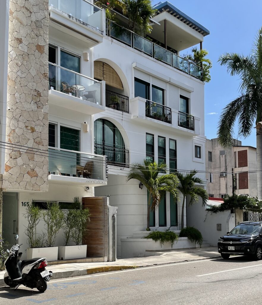 Peaceful residential street in the Gonzalo Guerrero area of Playa del Carmen, lined with modern apartment buildings and bathed in bright sunshine.
