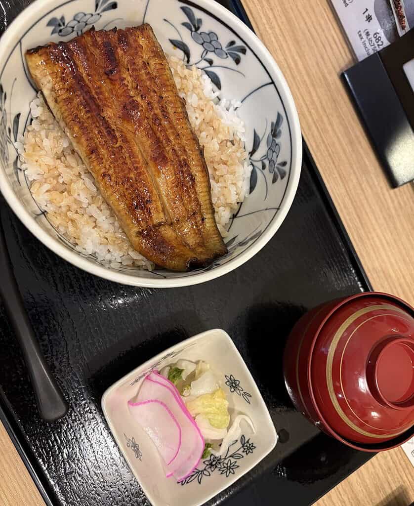 Traditional Japanese grilled eel served over rice on a lacquered tray with sides