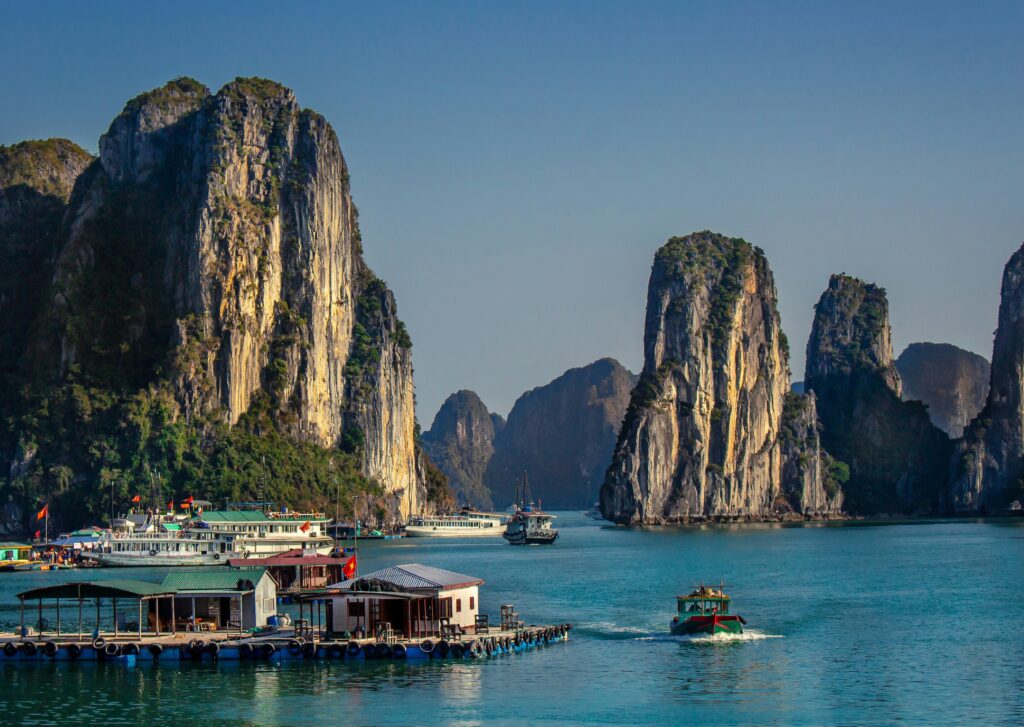 Picturesque landscape of Ha Long Bay with towering limestone cliffs and boats cruising through emerald waters.