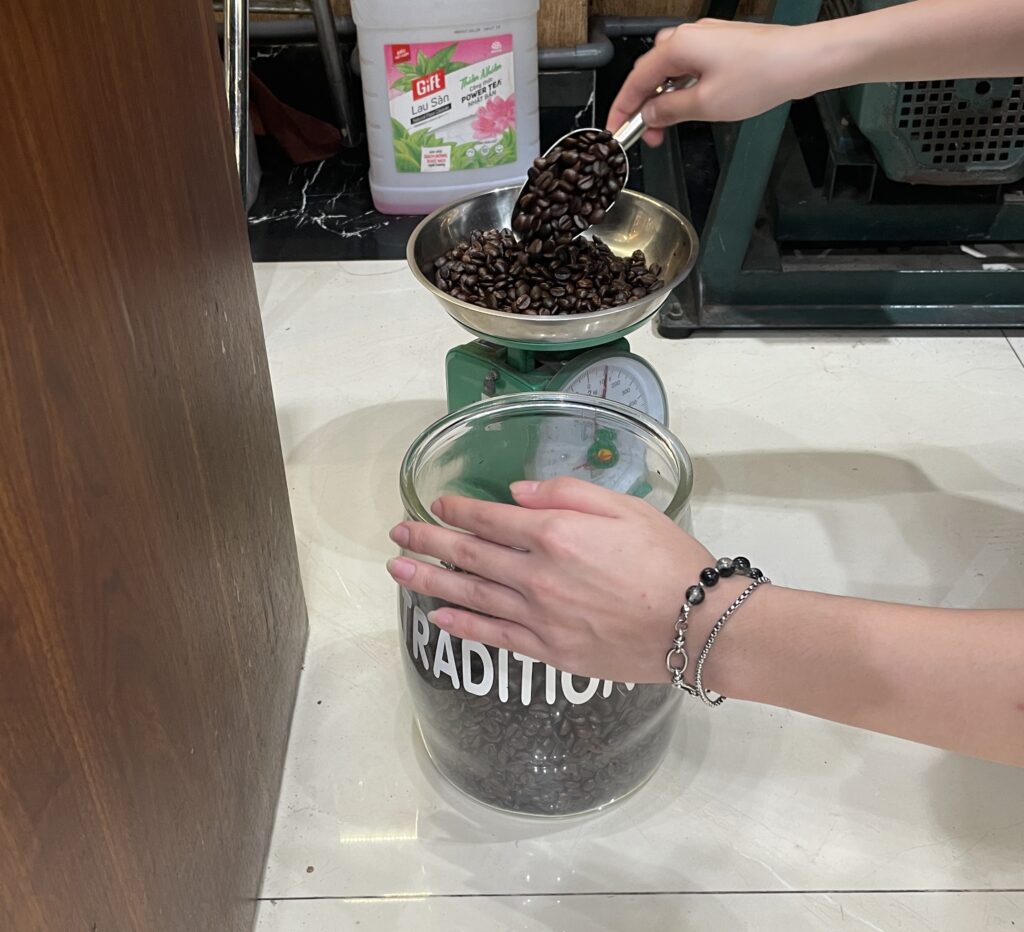 A local woman vendor in Hanoi pouring coffee beans at her market stall.