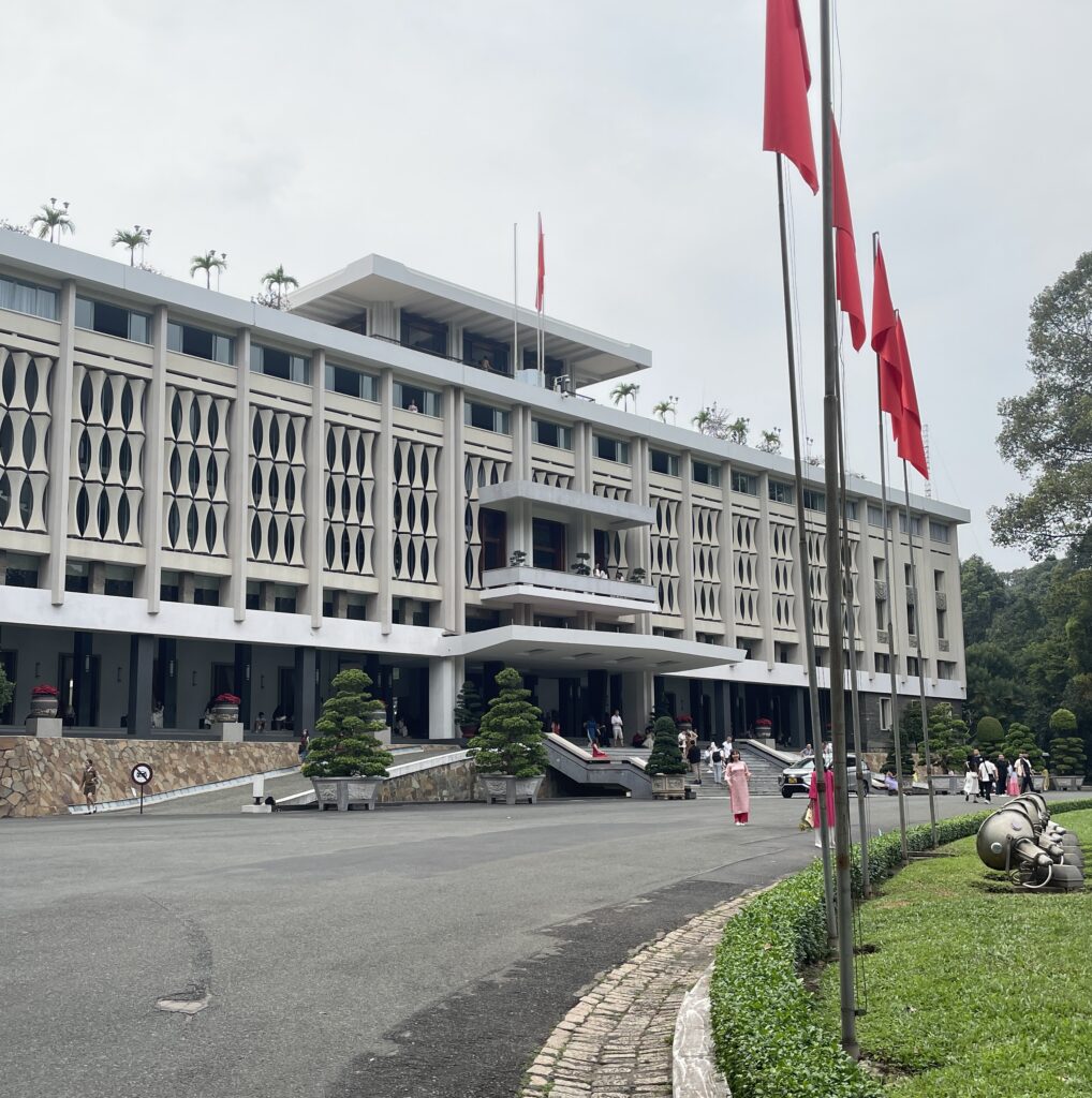 Front view of the Independence Palace in Ho Chi Minh City with clear blue skies and well-kept gardens in the foreground
