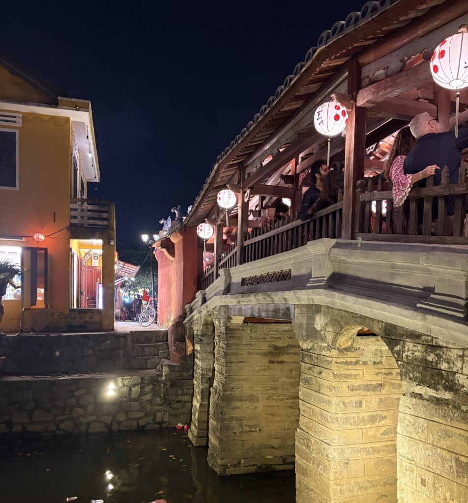 The Japanese Bridge in Hoi An beautifully lit at night with colorful lanterns adorning the structure and nearby area
