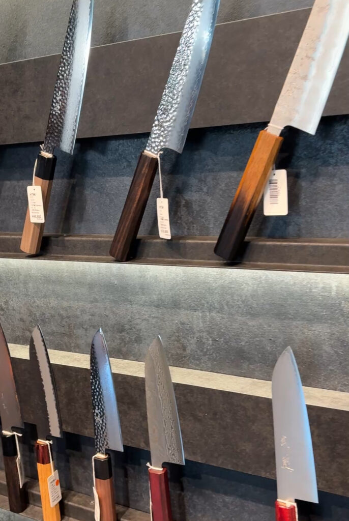 Traditional Japanese knives neatly displayed in a Kyoto shop, showcasing craftsmanship and polished steel blades.