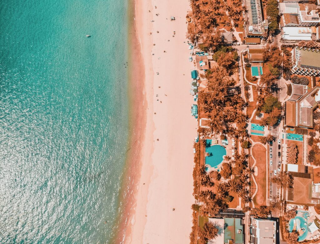 Overhead drone view of Kata Noi Beach showing turquoise waters, golden sand, and lush greenery in Phuket, Thailand
