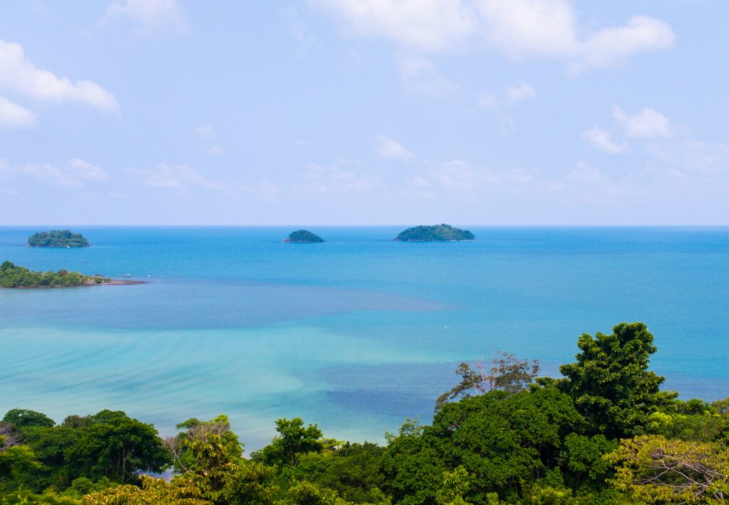 Viewpoint overlooking dense forest and vibrant blue water in Koh Chang, Thailand